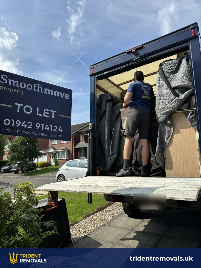 Trident Removals team member loading blanket-wrapped furniture into the van